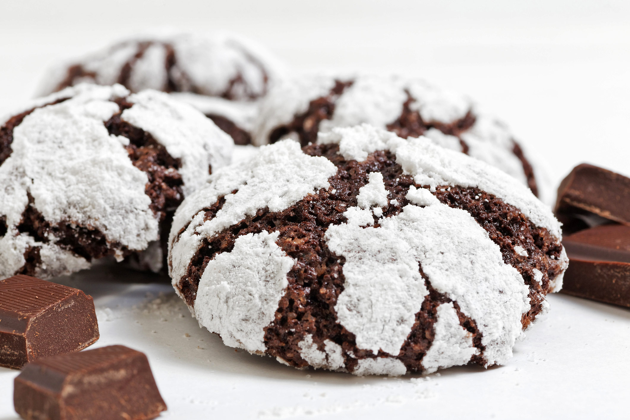 Stacks of crinkle cookies on white plate and white background, some with chocolate chunks around the base; Fudge Drop Crinkle Cookies, Jane Bonacci, The Heritage Cook.