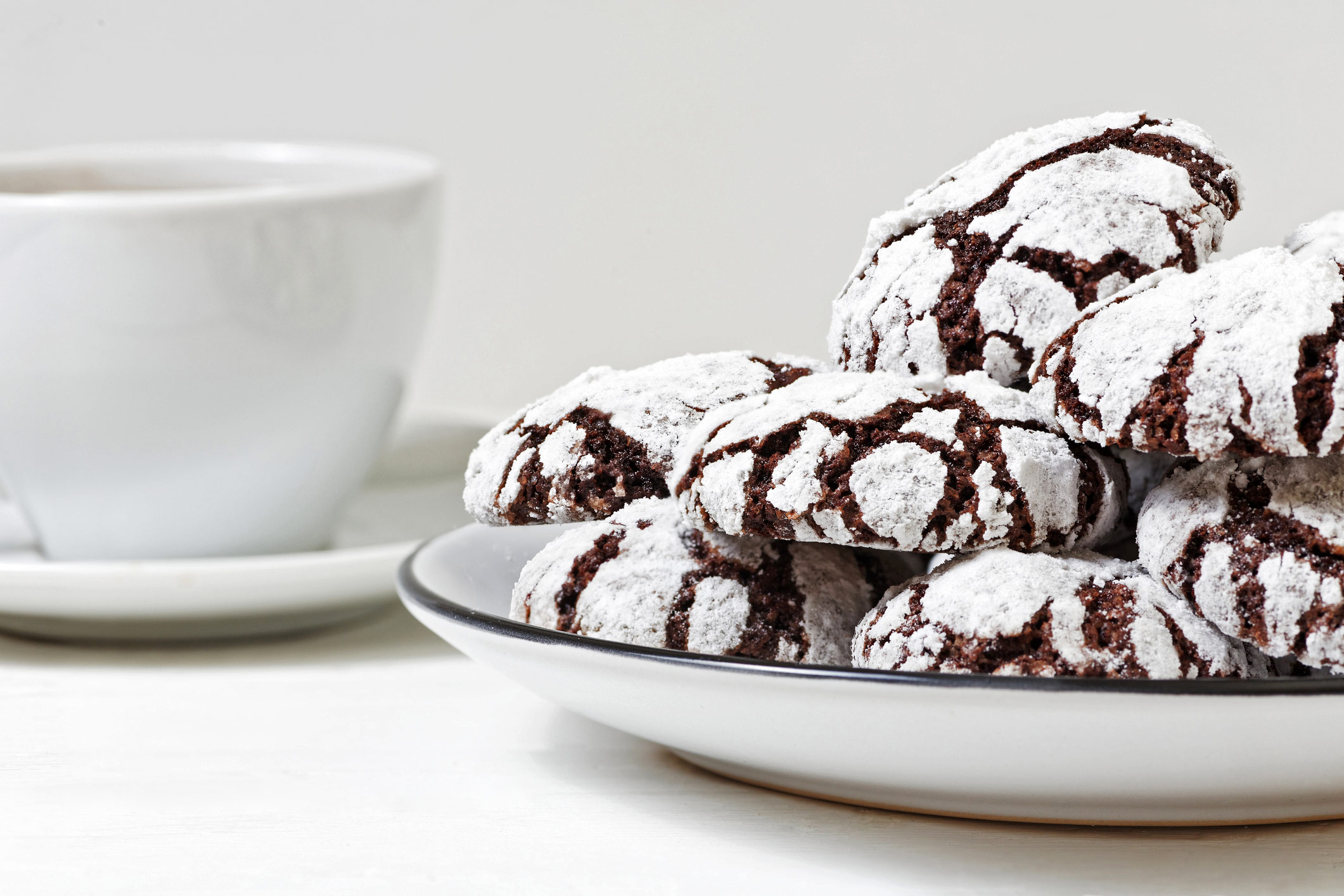 Stacks of crinkle cookies on white plate and white background, some with chocolate chunks around the base; Fudge Drop Crinkle Cookies, Jane Bonacci, The Heritage Cook. 