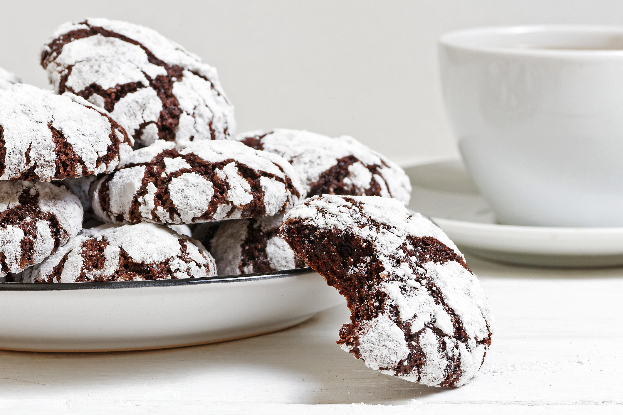 Stacks of crinkle cookies on white plate and white background, some with chocolate chunks around the base; Fudge Drop Crinkle Cookies, Jane Bonacci, The Heritage Cook. 