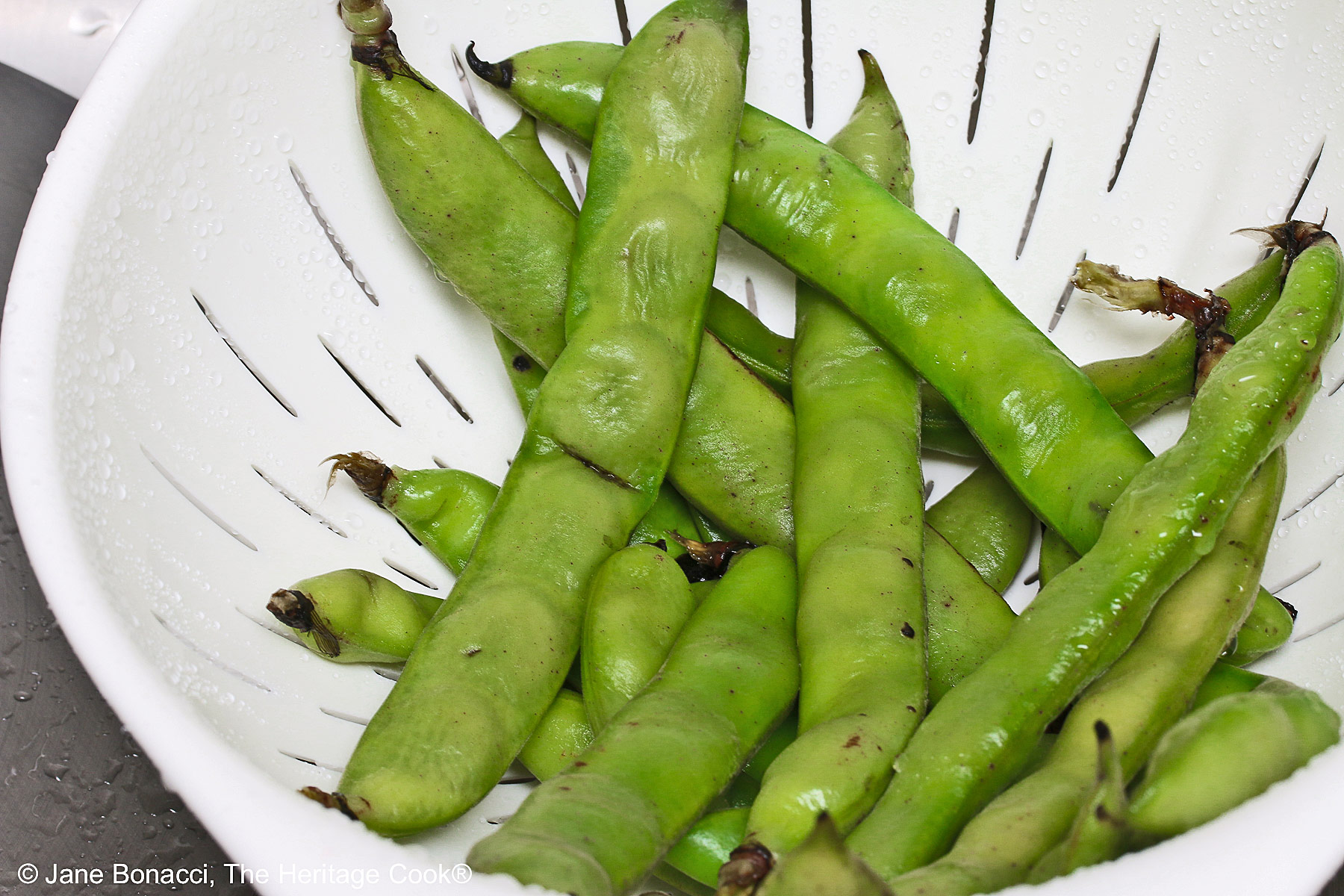 Steamed fava bean pods in a colander. 
