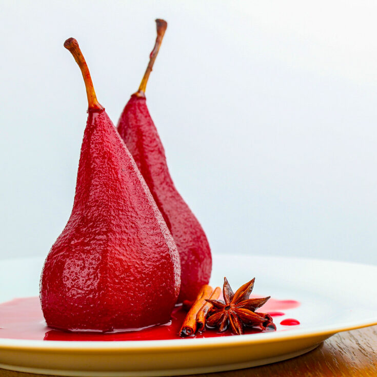 Pears, stained red by the red wine poaching liquid, on white plate, perfect for the holidays or any special occasion; Red Wine Poached Pears, Jane Bonacci, The Heritage Cook.