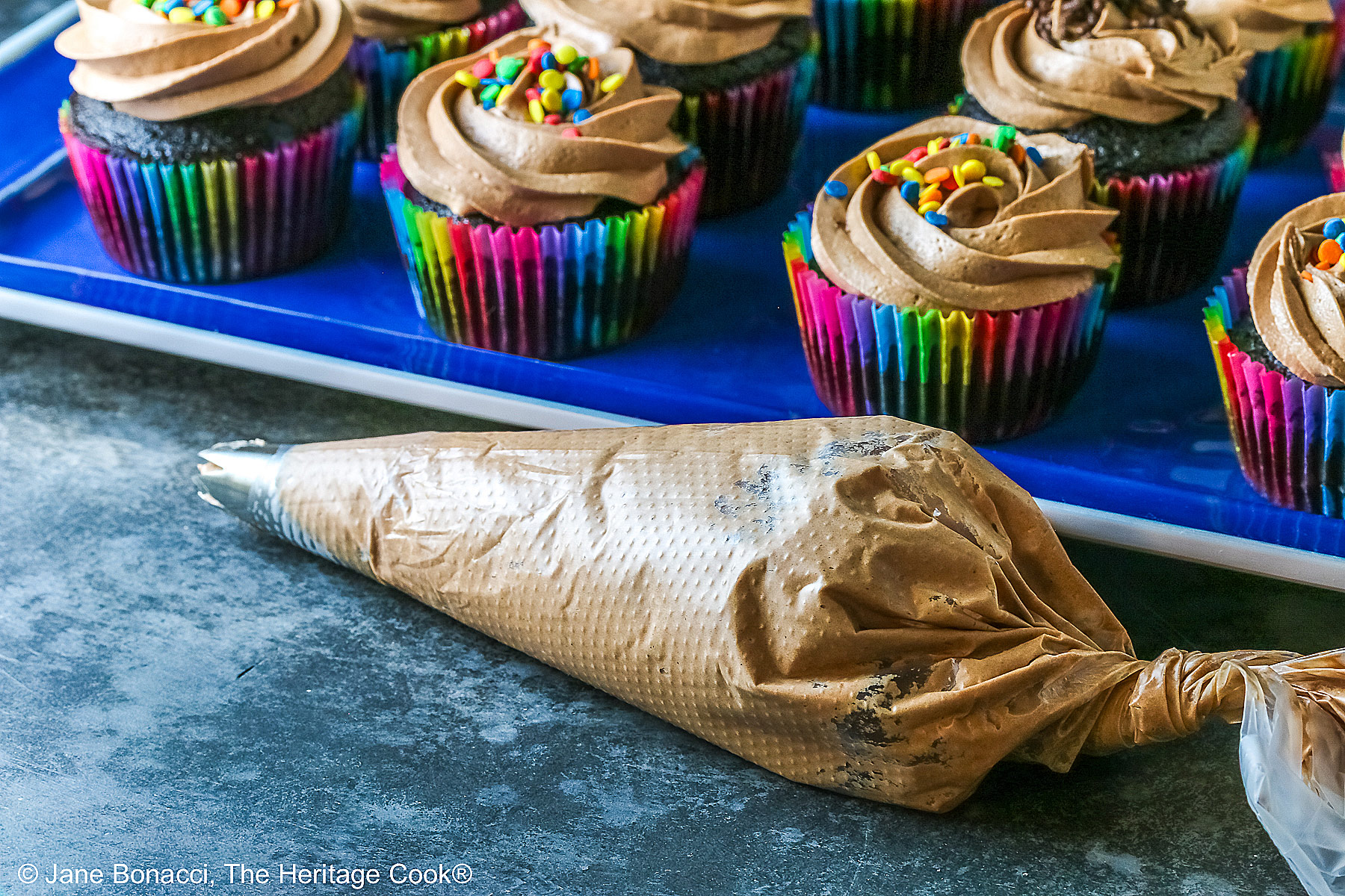 A piping bag filled with Nutella frosting in front of the platter of cupcakes.