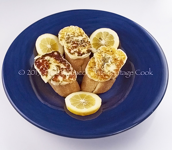 Grilled Halloumi cheese on baguette slices, drizzled with fresh lemon juice