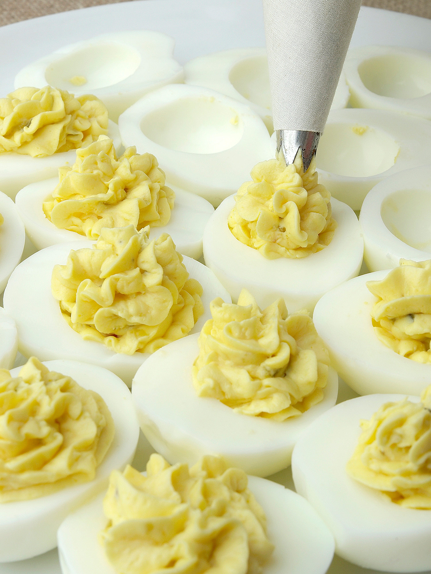 Piping yolk mixture into cooked egg white halves. 