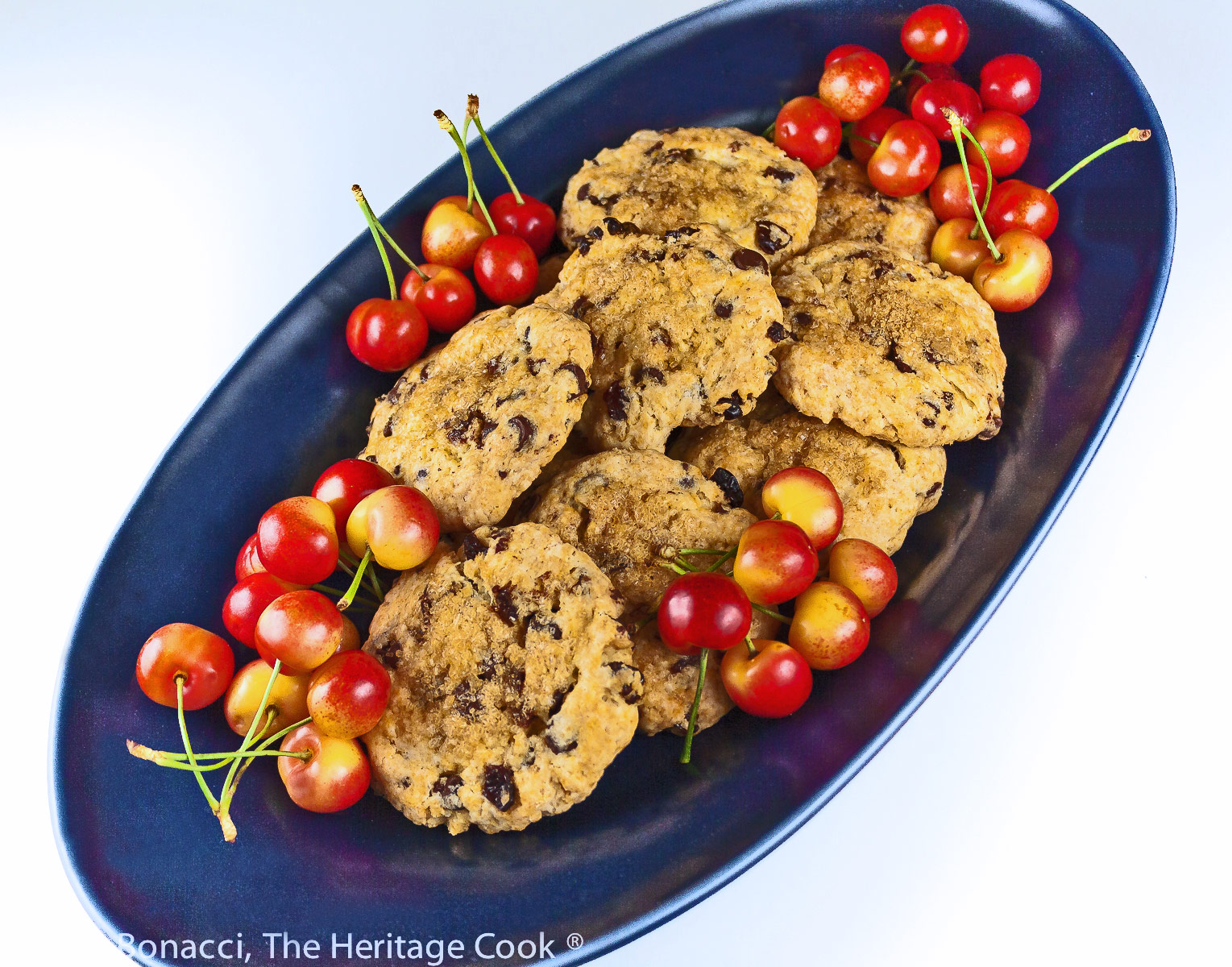 Pile of beautifully baked Chocolate Chip Cherry Scones on a dark blue oval platter; Chocolate Chip Cherry Cream Scones © 2022 Jane Bonacci, The Heritage Cook. 