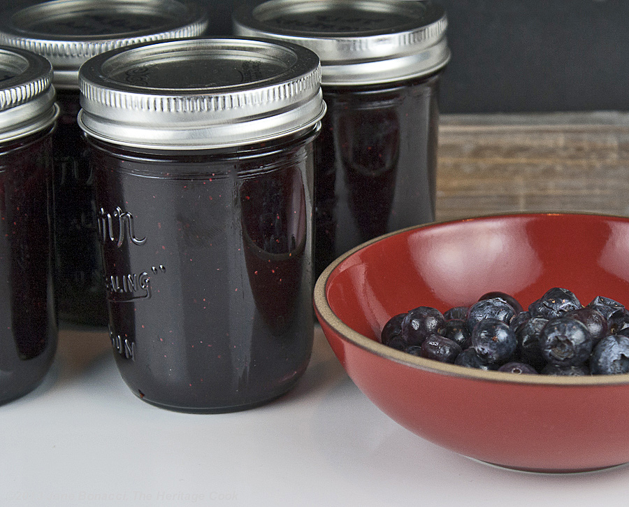 Homemade Blueberry Jam from The Heritage Cook; jars next to bowl of berries