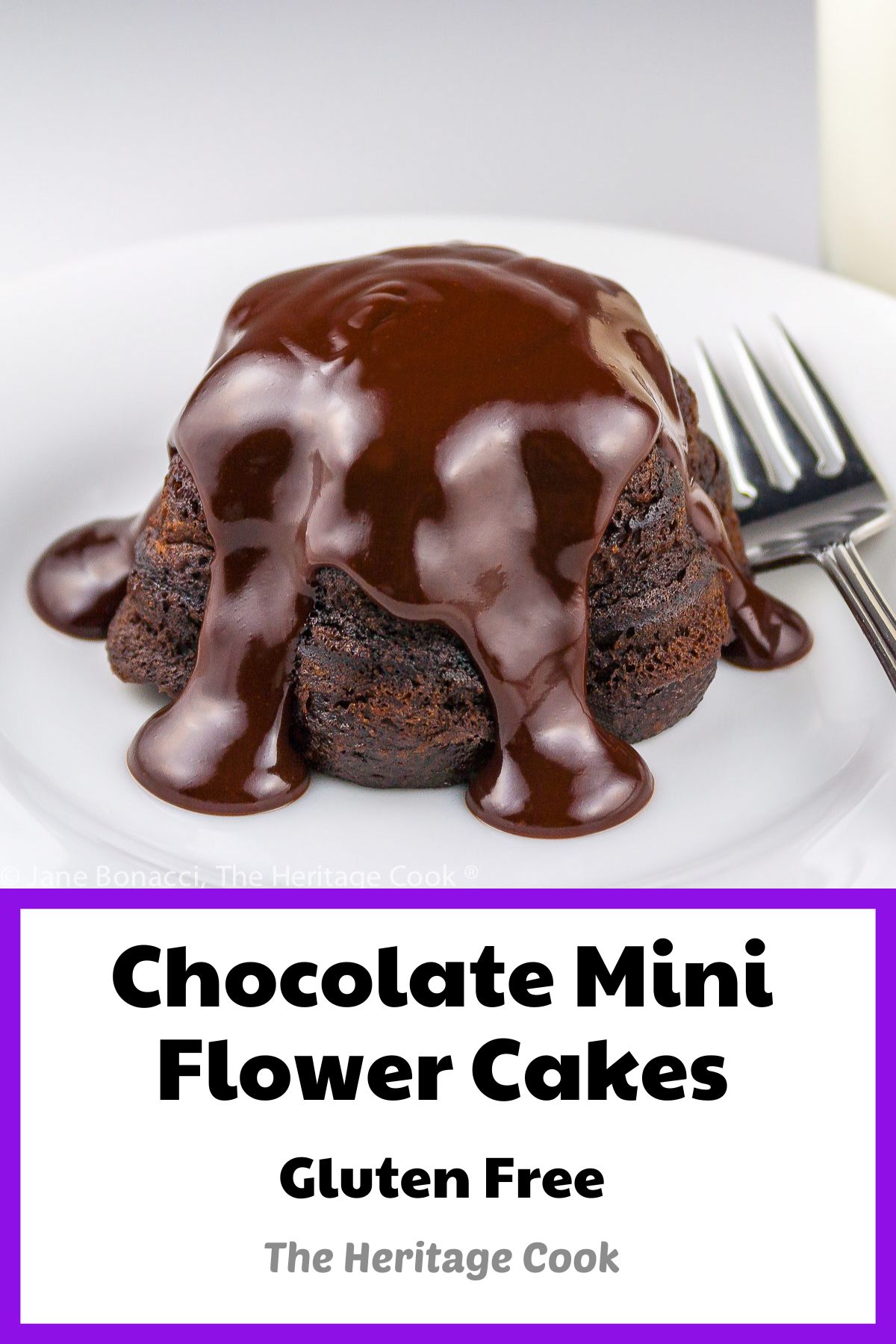 Flower-shaped mini chocolate cakes covered in a thick, rich chocolate ganache on a white plate with a glass of milk behind it; Chocolate Mini Flower Cakes © 2023 Jane Bonacci, The Heritage Cook. 