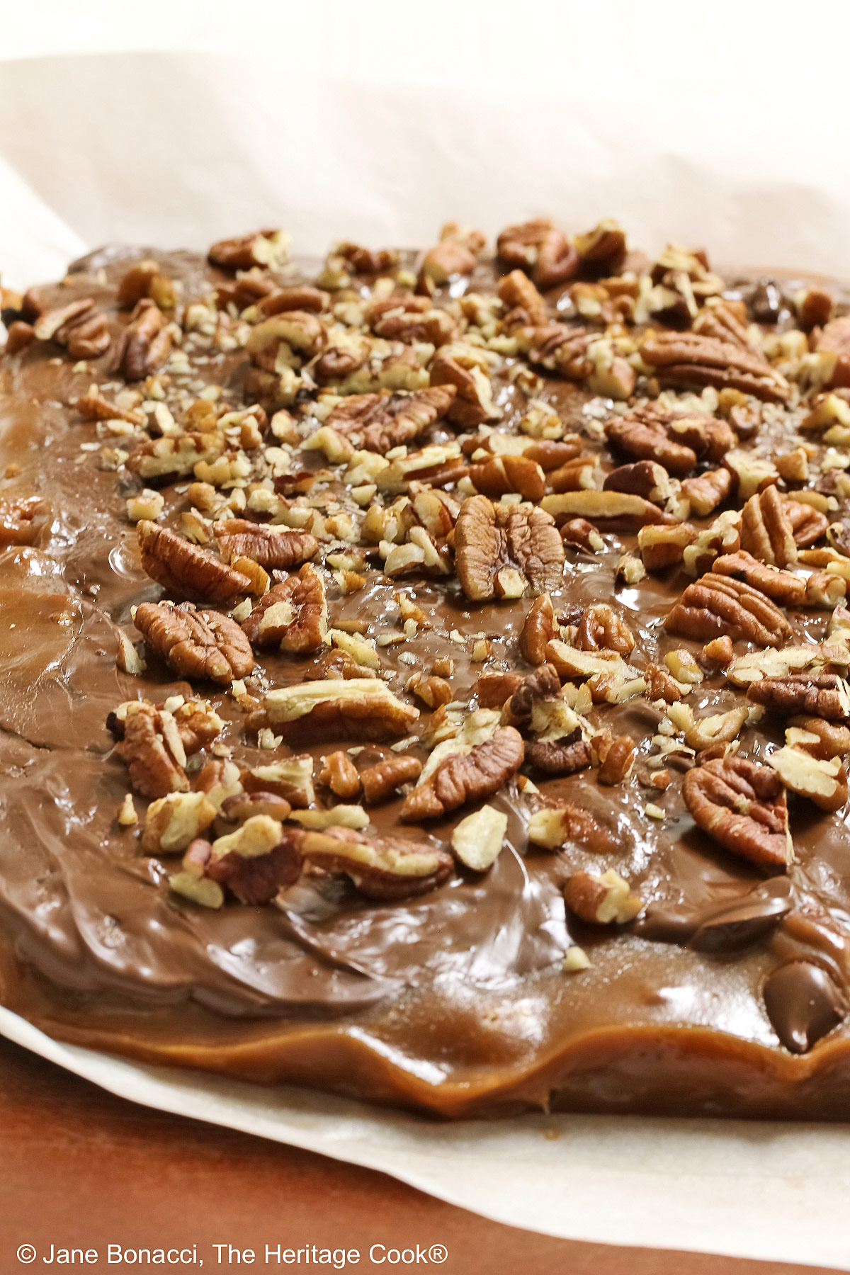 Pulling the parchment paper away from the caramel bars.