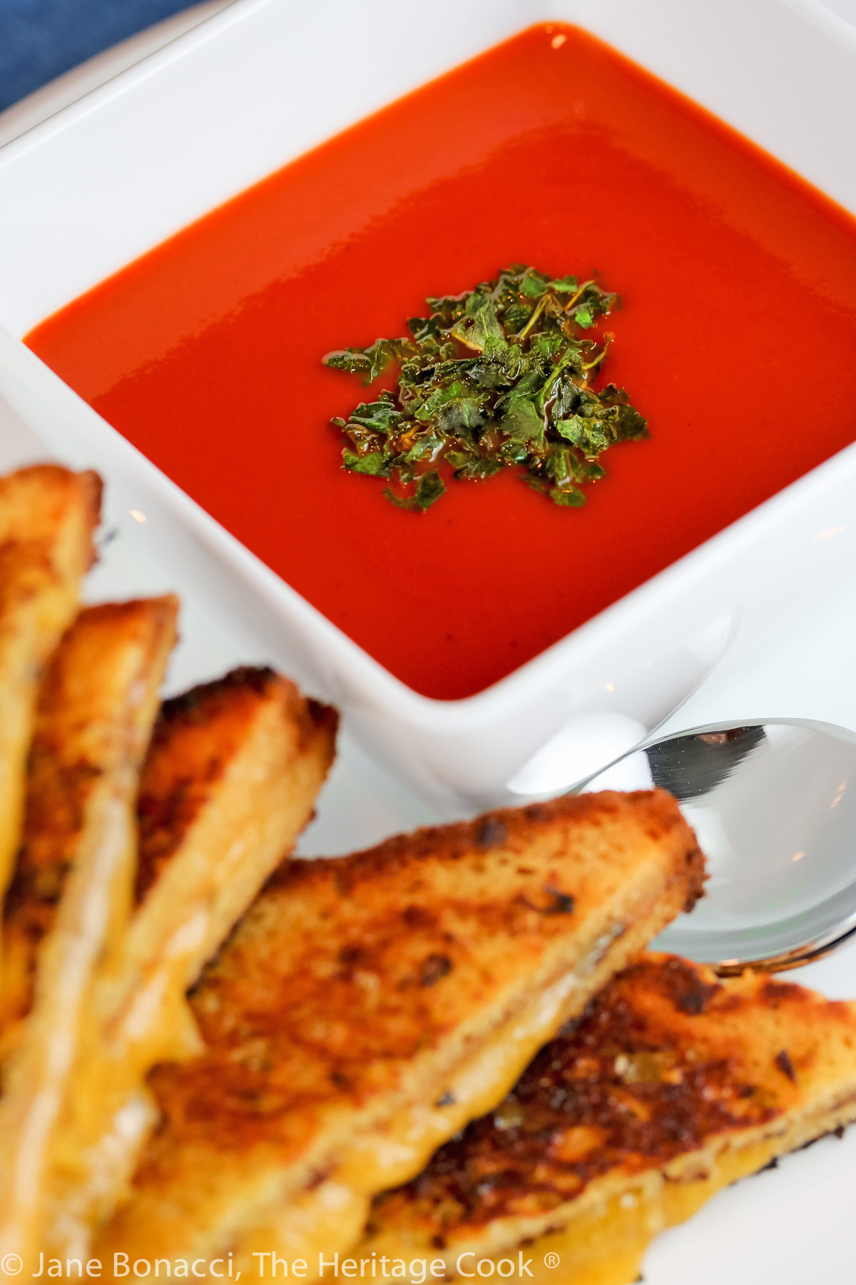 White bowls of red tomato soup with green garnish on top and grilled cheese sandwiches on the side; Italian Cream of Tomato Soup © 2023 Jane Bonacci, The Heritage Cook. 