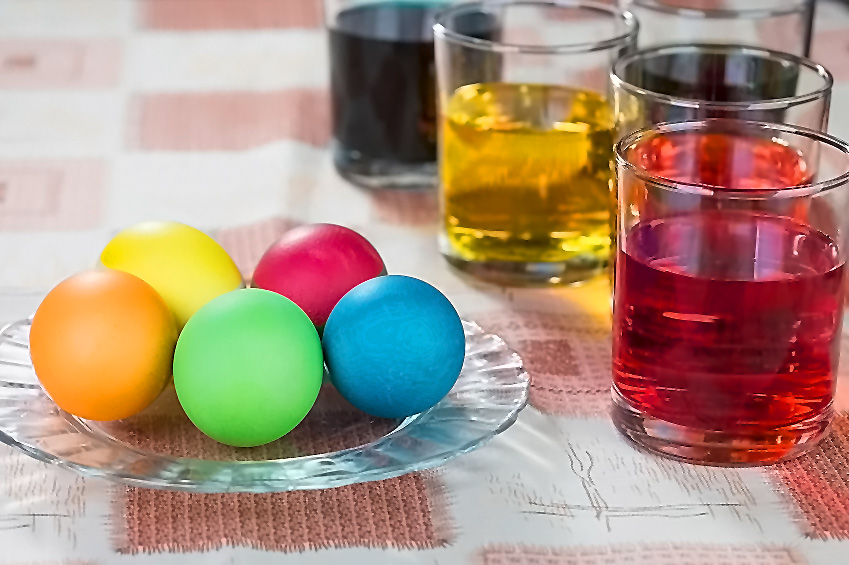 Plate with brightly colored Easter Eggs and glasses with beautiful dyes