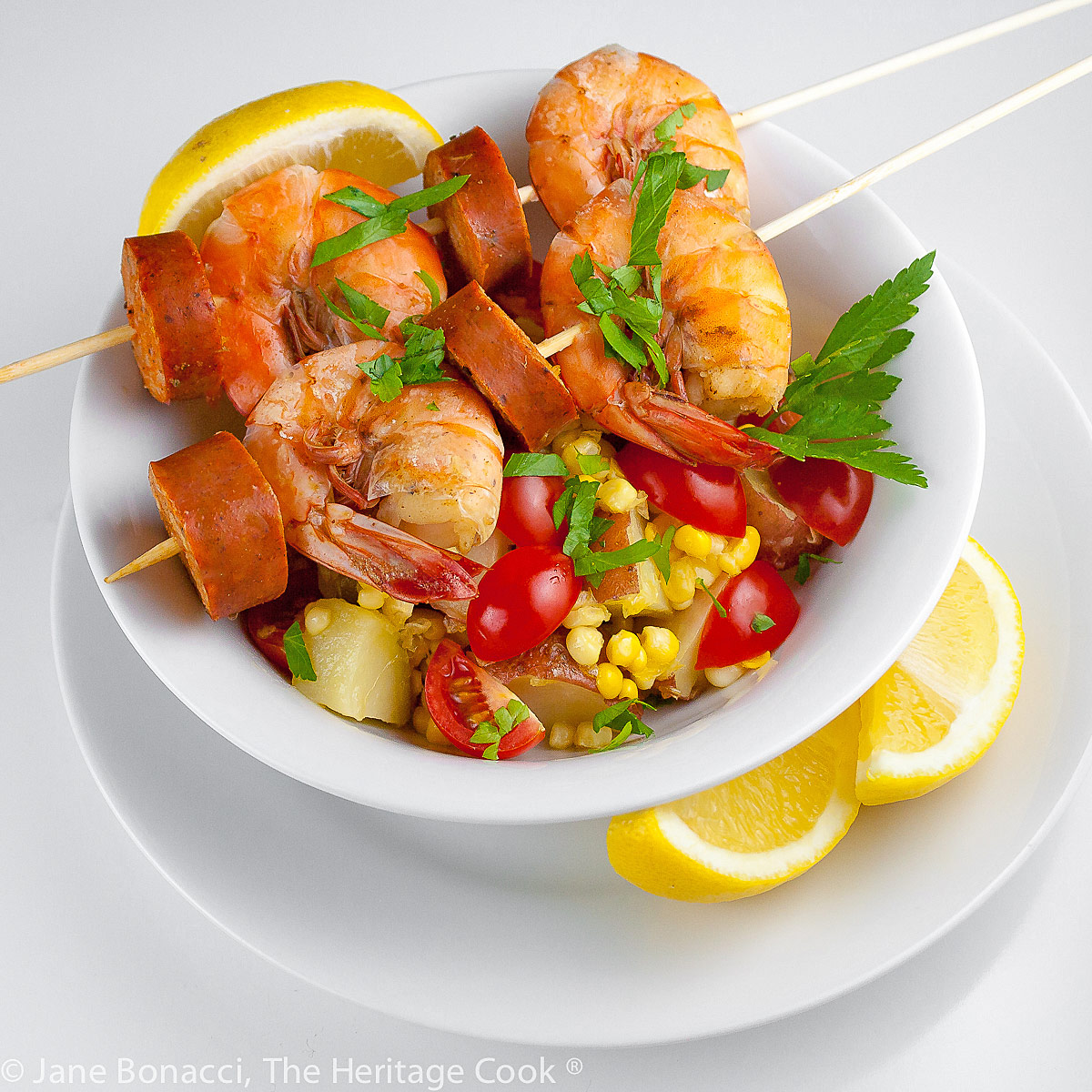 Bowl with fresh corn, potatoes and tomatoes topped by Shrimp Boil Skewers © 2022 Jane Bonacci, The Heritage Cook