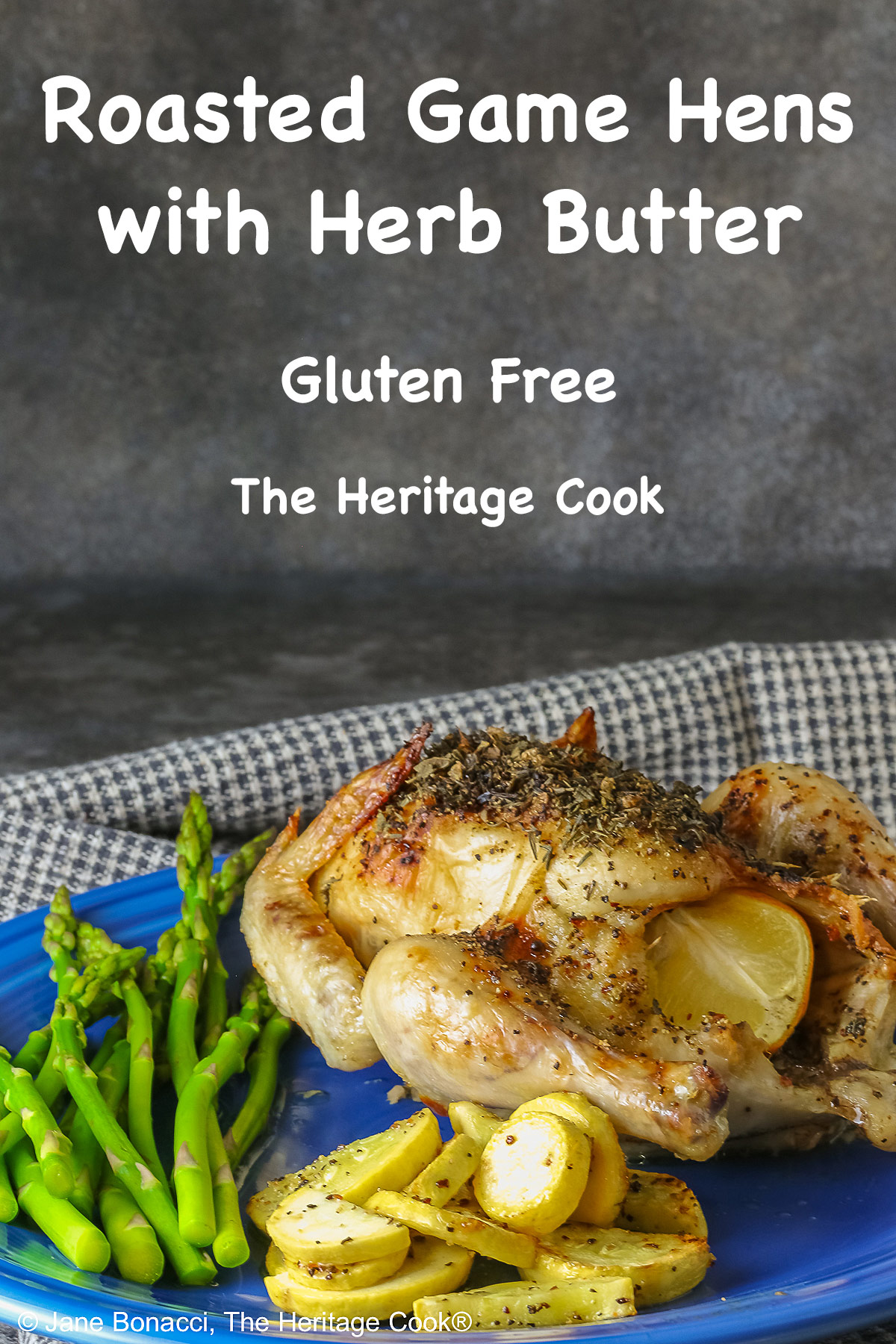 A Roasted Game Hen with Herb Butter for Valentine's Day on a deep blue plate with sauteed yellow squash and steamed asparagus, sitting on a checked cloth © 2025 Jane Bonacci, The Heritage Cook. 