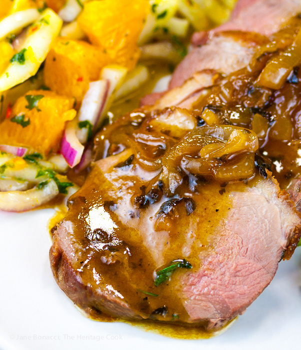 Close up of sliced orange duck breast served with pan sauce and orange-fennel salsa