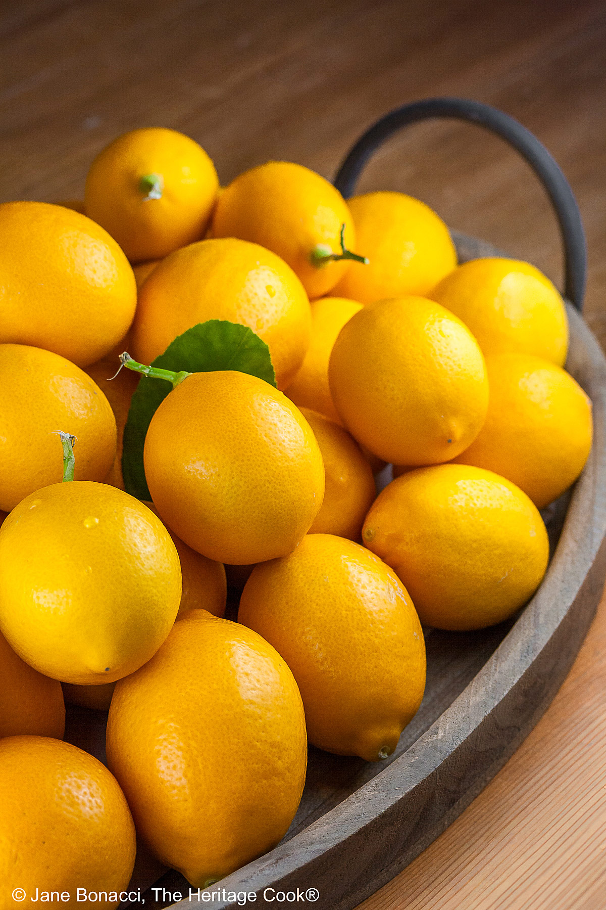 Large pile of Meyer lemons on a tray with handles.