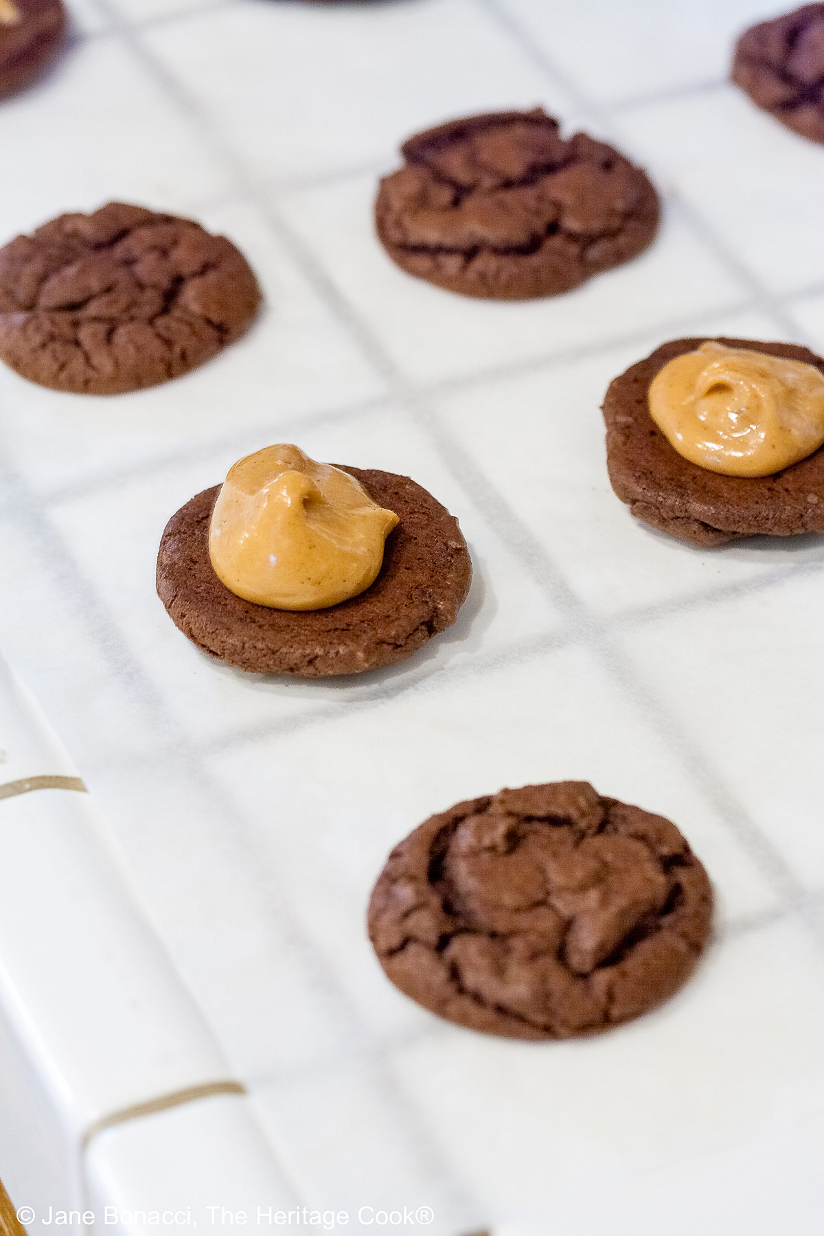 Cooled cookies being filled with the peanut butter filling.