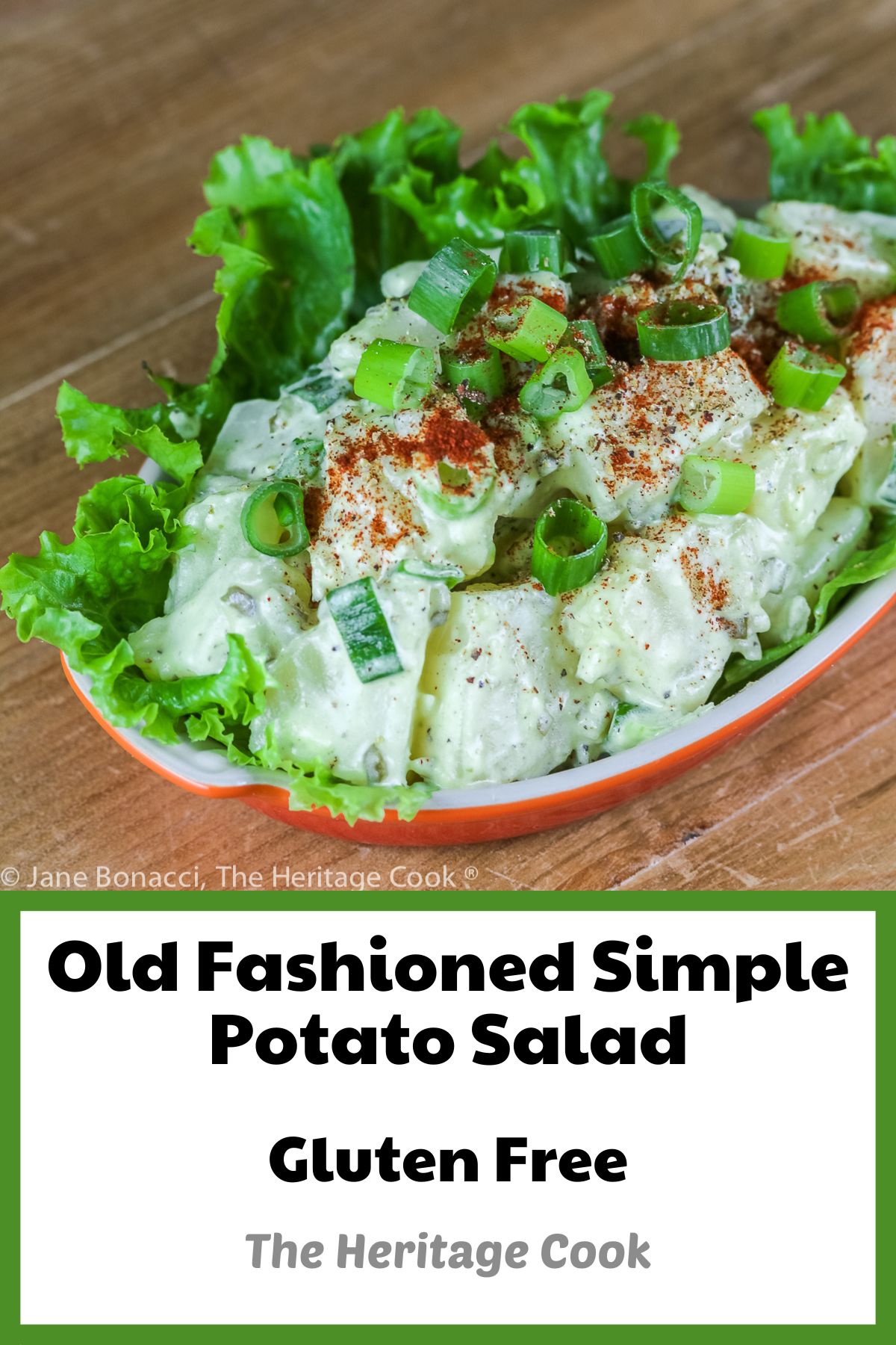 Old Fashioned Simple Potato Salad (Gluten-Free) piled in a lettuce leaf-lined red au gratin dish, sprinkled with green onions and paprika; © 2023 Jane Bonacci, The Heritage Cook.