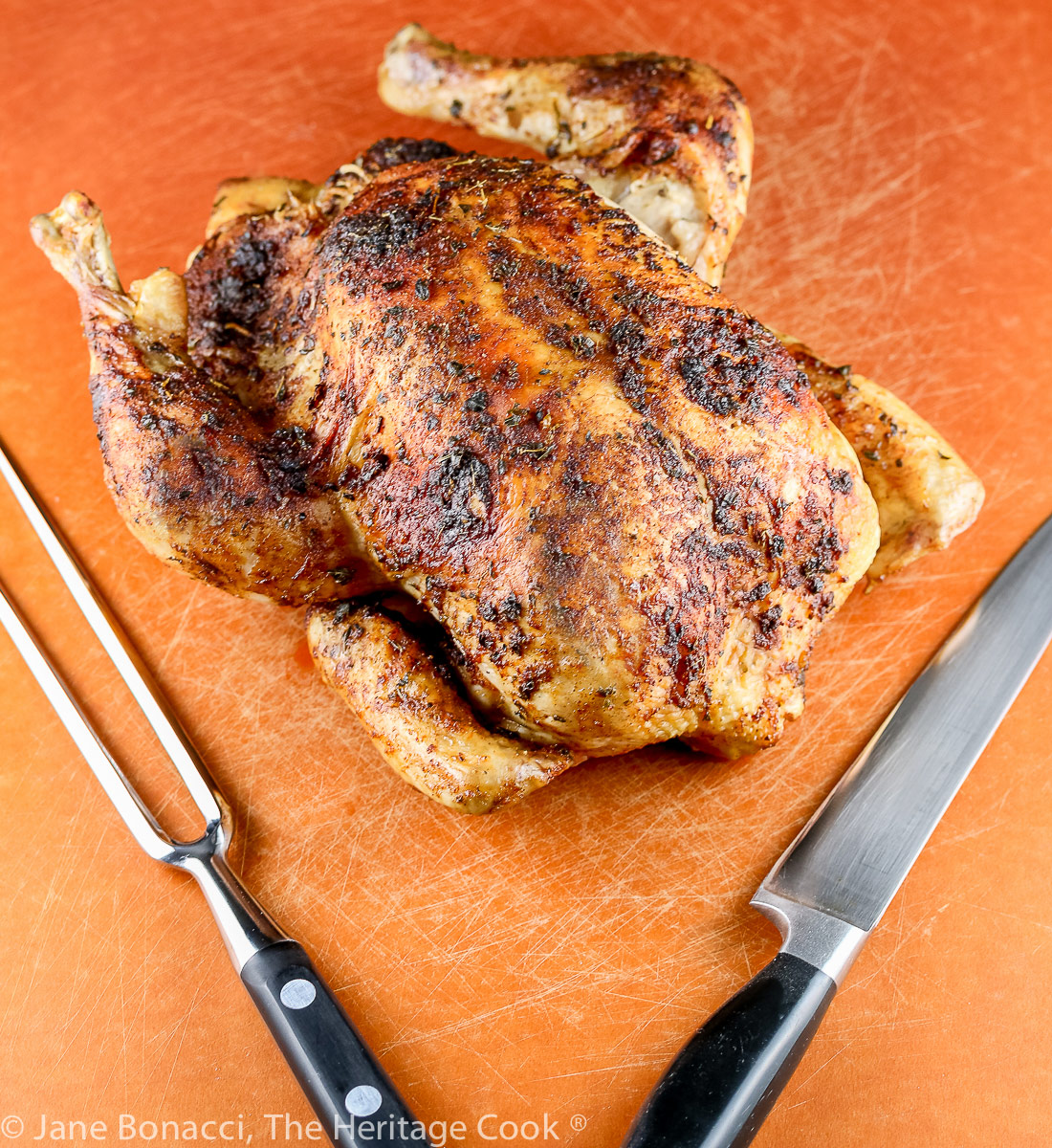Chicken ready for carving with a large fork and knife