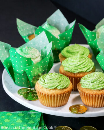 Vanilla cupcakes in festive cupcake papers, some with green frosting and some with white and green sugar sprinkles; Festive luscious chocolate chip buttermilk cupcakes with a surprise inside, perfect for any holiday © 2023 Jane Bonacci, The Heritage Cook.