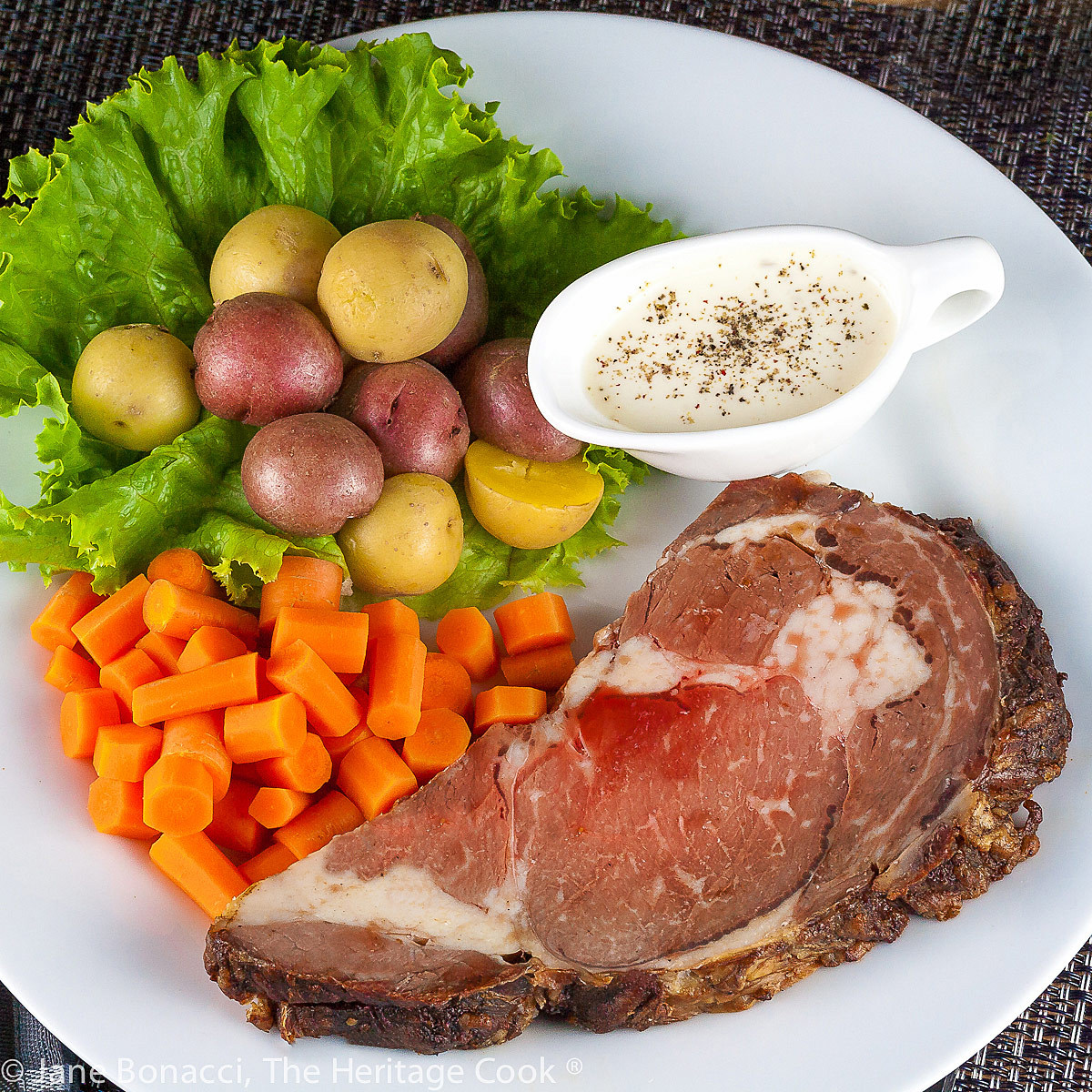 Grilled prime rib beef roast is sliced and served with carrots and potatoes; Succulent Grilled Prime Rib Roast © 2022 Jane Bonacci, The Heritage Cook. 