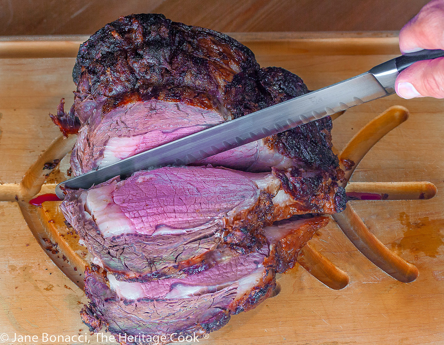Knife slicing through the perfectly cooked prime rib roast. 