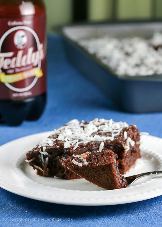 Bottle of root beer, whole cake and slice of Root Beer Chocolate Cake in front; Root Beer Chocolate Cake with Root Beer Glaze © 2018 Jane Bonacci, The Heritage Cook 