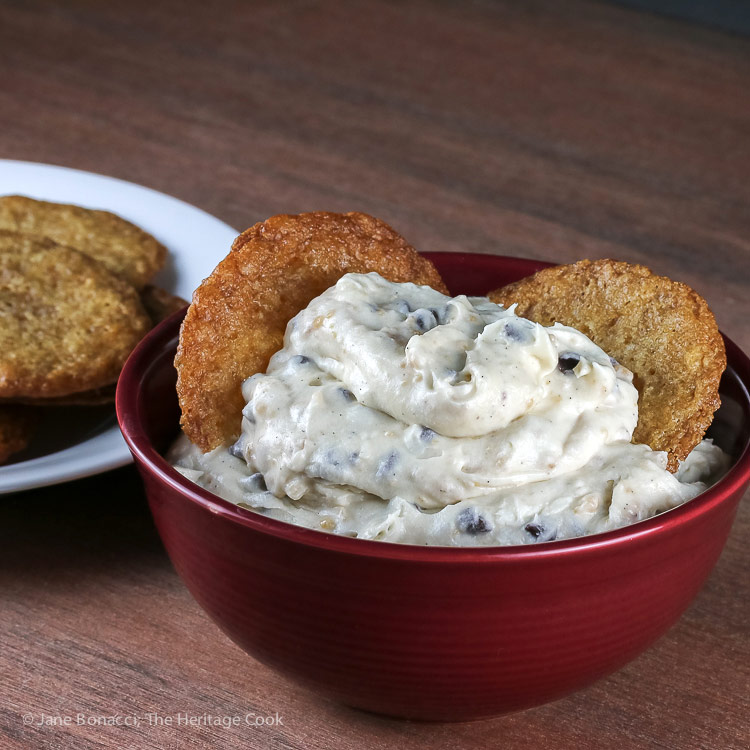 bowl of cheesecake dip with 2 cookies and plate of cookies behind; Chocolate Chip Toffee Cheesecake Cookie Dip © 2018 Jane Bonacci, The Heritage Cook