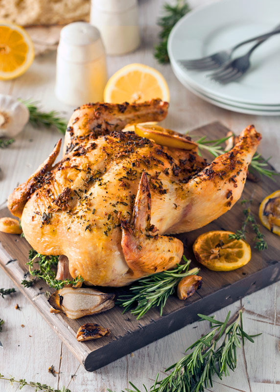 whole chicken on a board with lemon slices around; Lemon and Cumin Scented Chicken from The Heritage Cook 2018 Jane Bonacci, The Heritage Cook