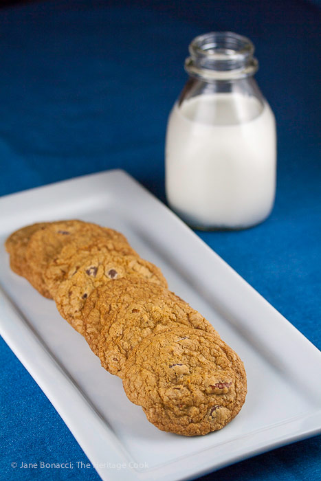 Line of cookies on platter with bottle of milk in back; Orange Scented Gluten Free Chocolate Chip Cookies © 2018 Jane Bonacci, The Heritage Cook