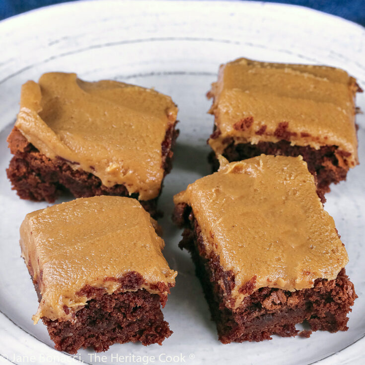 Squares of brownies topped with thick peanut butter frosting, on a white plate with a blue background; © 2023 Jane Bonacci, The Heritage Cook.