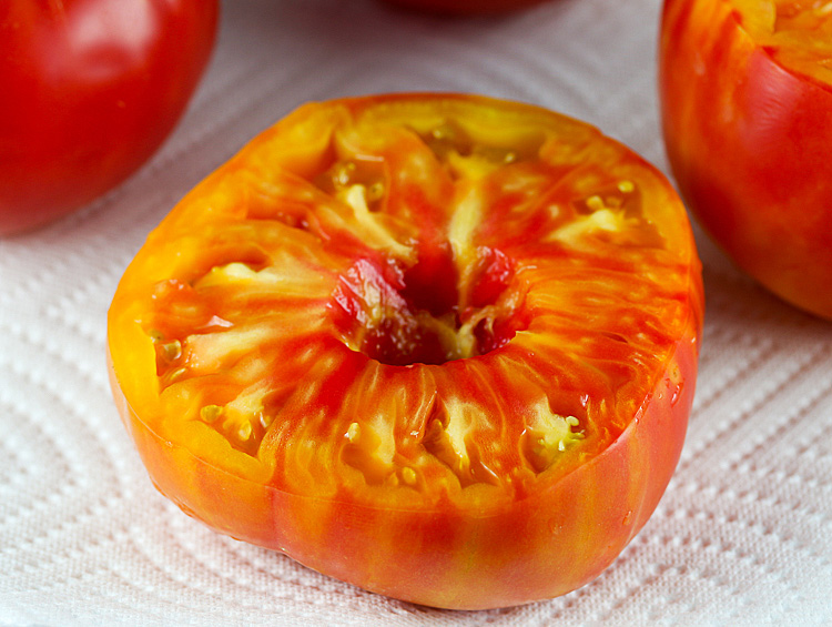 Close up of halved orange heirloom tomato, ready for stuffing