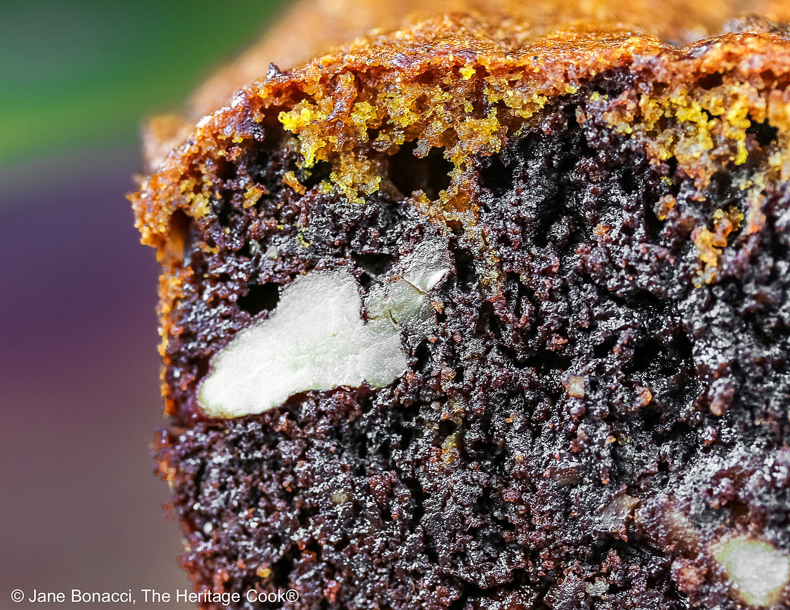 Pumpkin Swirl Brownies cut into squares and sitting on a dark plate, some stacked 3 high with a dark background that highlights the contrast between the dark brownies on the bottom with a topping of golden pumpkin cake on each piece © 2026 Jane Bonacci, The Heritage Cook.