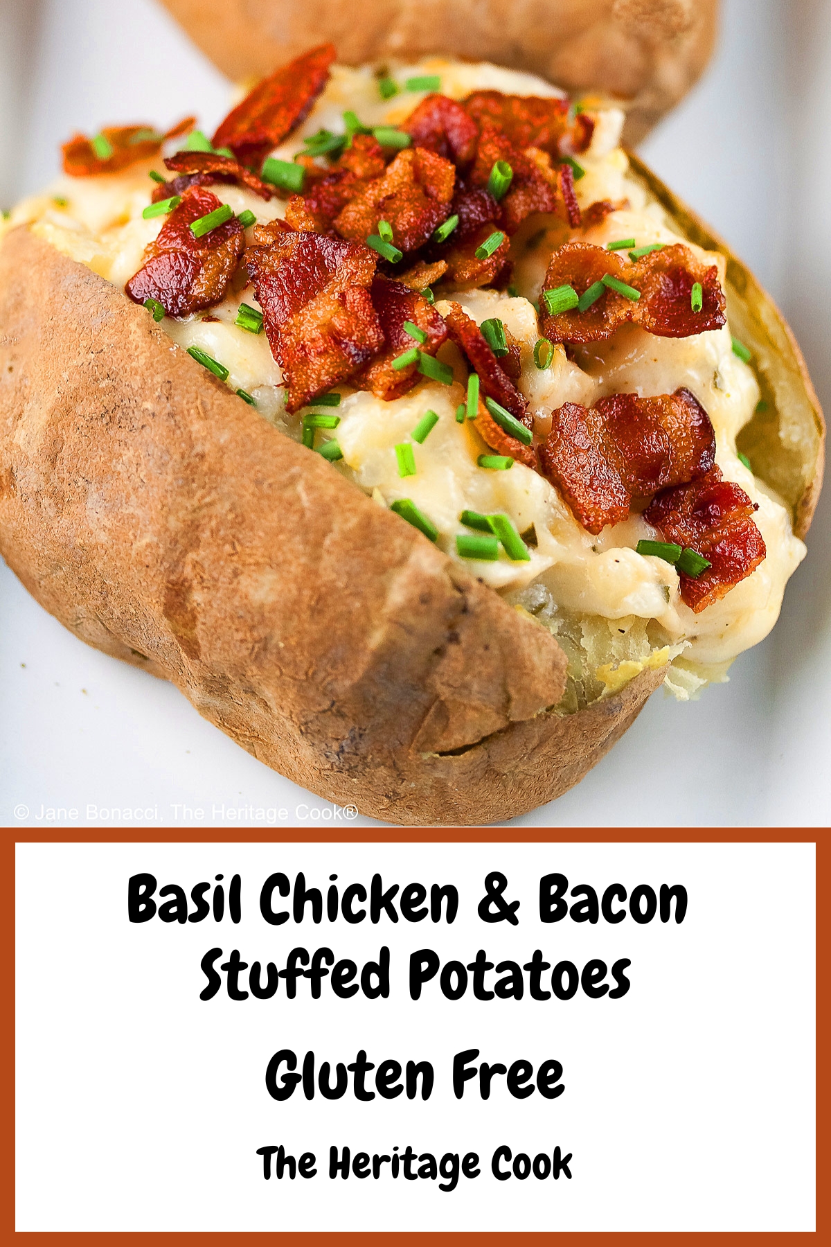 Baked potatoes split lengthwise and stuffed with a creamy cheese sauce with chicken, sitting on a white rectangle platter with a black background, topped with chopped bacon and chopped chives © 2025 Jane Bonacci, The Heritage Cook.