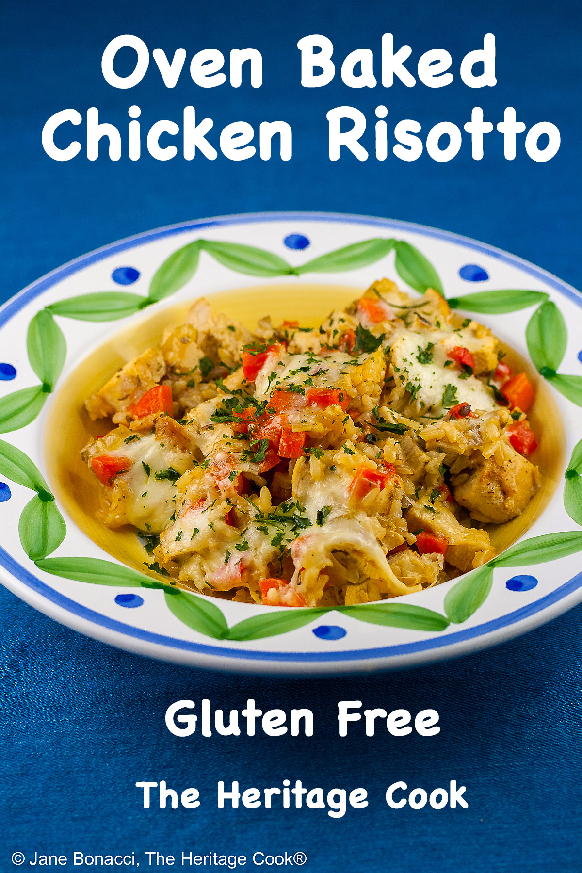 Golden rice mixed with red bell peppers, onions, and chicken, sprinkled with green parsley, this Oven Baked Chicken Risotto is in a bowl with a wide rim decorated with green and blue, sitting on a vivid blue background © 2026 Jane Bonacci, The Heritage Cook.