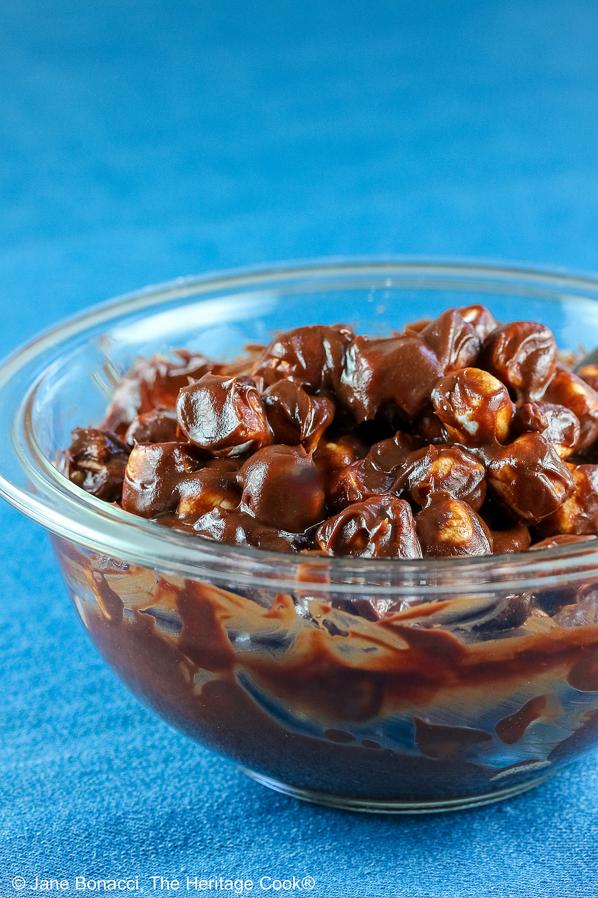 Bowl of frosting with nuts and marshmallows on a blue backdrop.