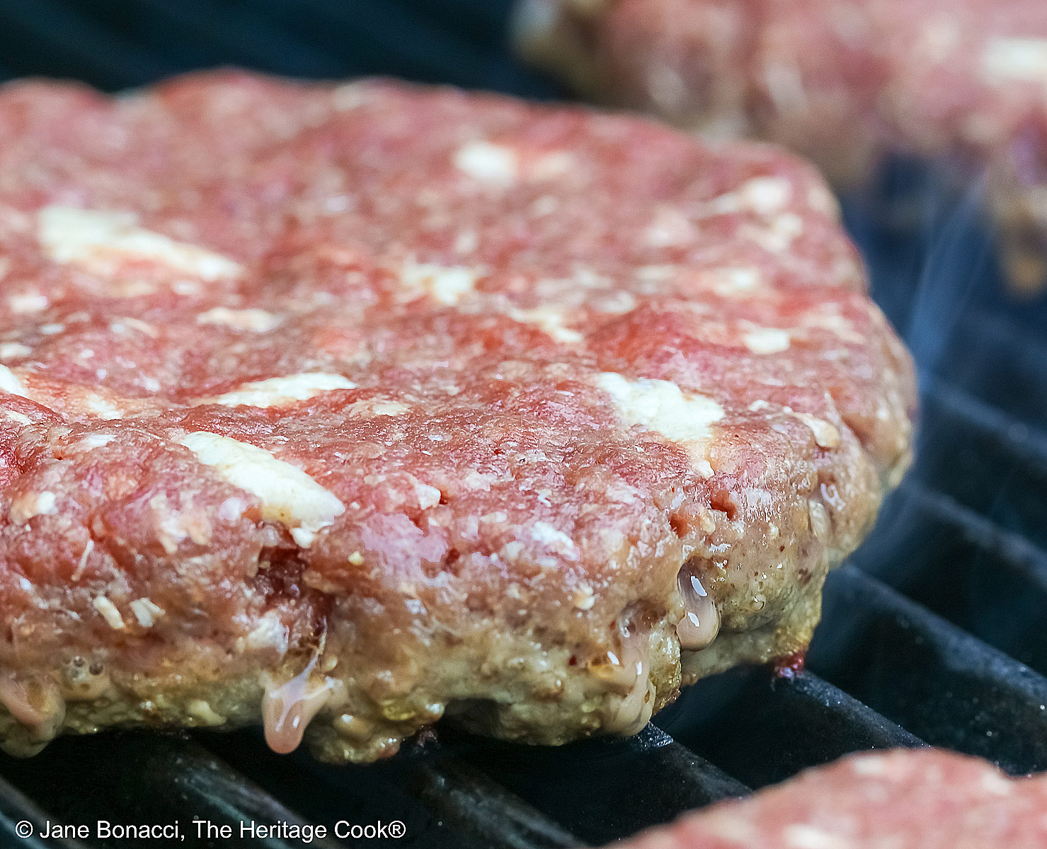 Buffalo patty studded with bacon fat on the grill.