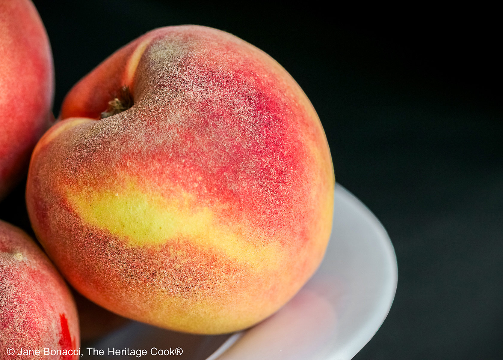 Bowl of peaches with focus on a single peach.
