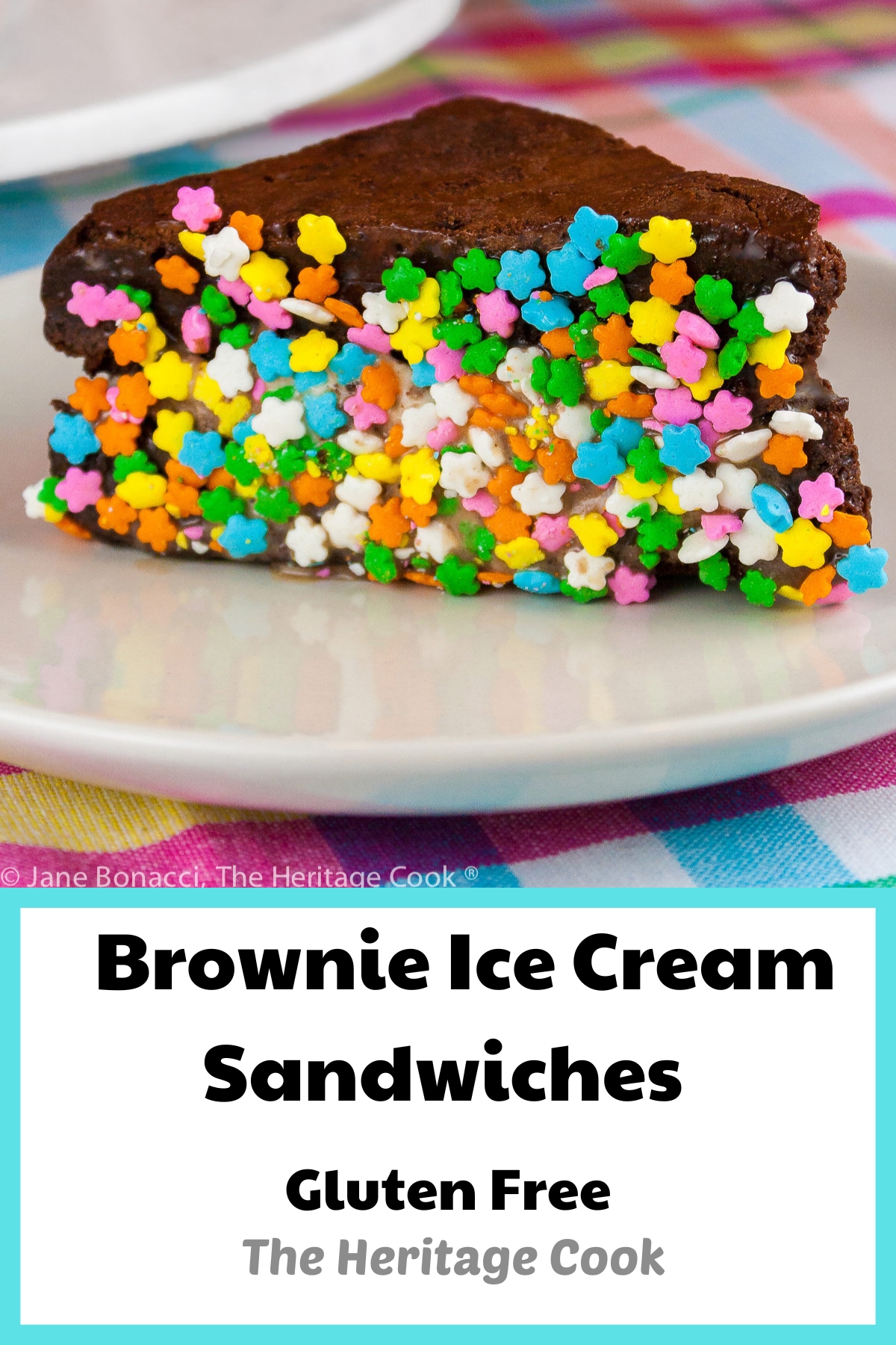 Triangular Brownie Ice Cream Sandwiches with the edges dipped in a variety of items, with a white plate in front with a single ice cream sandwich dipped in rainbow sprinkles on it, sitting on a brightly colored pastel checked cloth © 2026 Jane Bonacci, The Heritage Cook.