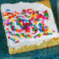 Square blondie with rainbow sprinkles on top on blue plate; White Chocolate Vanilla Blondies © 2022 Jane Bonacci, The Heritage Cook.