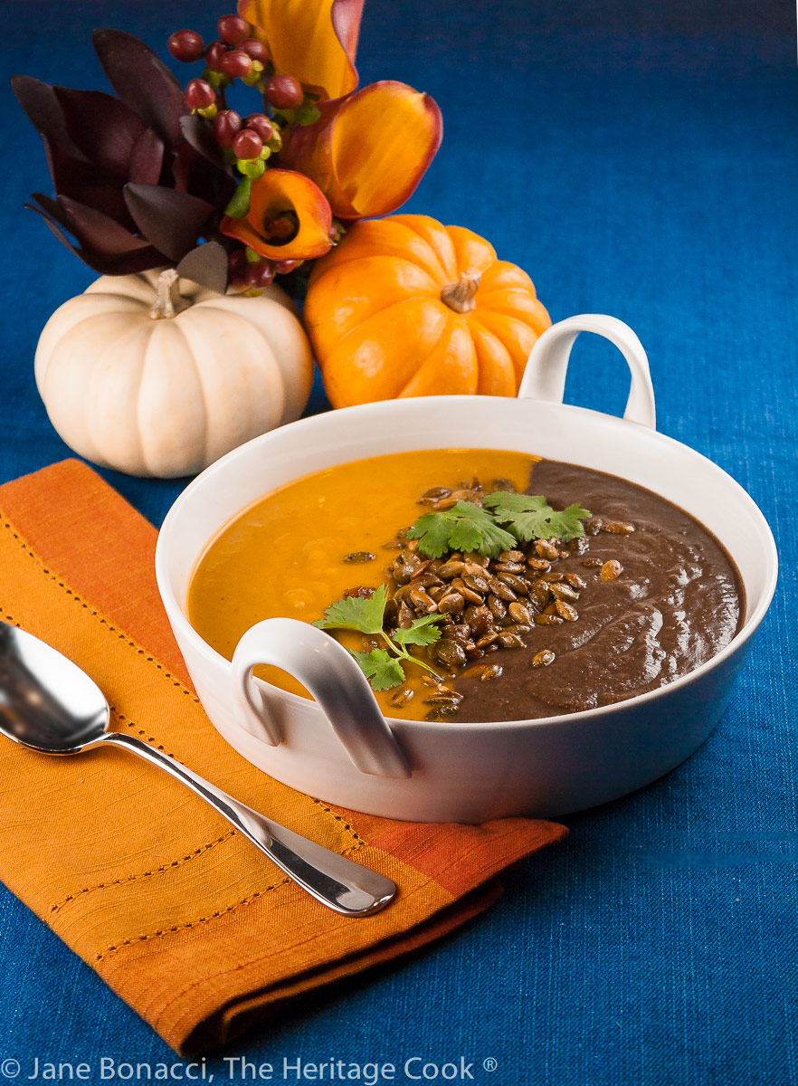 A bowl with two soups side by side, one orange, and the other black; Jack O’ Lantern Soup; Butternut Squash-Carrot Soup & Spicy Black Bean Soup © 2022 Jane Bonacci, The Heritage Cook.