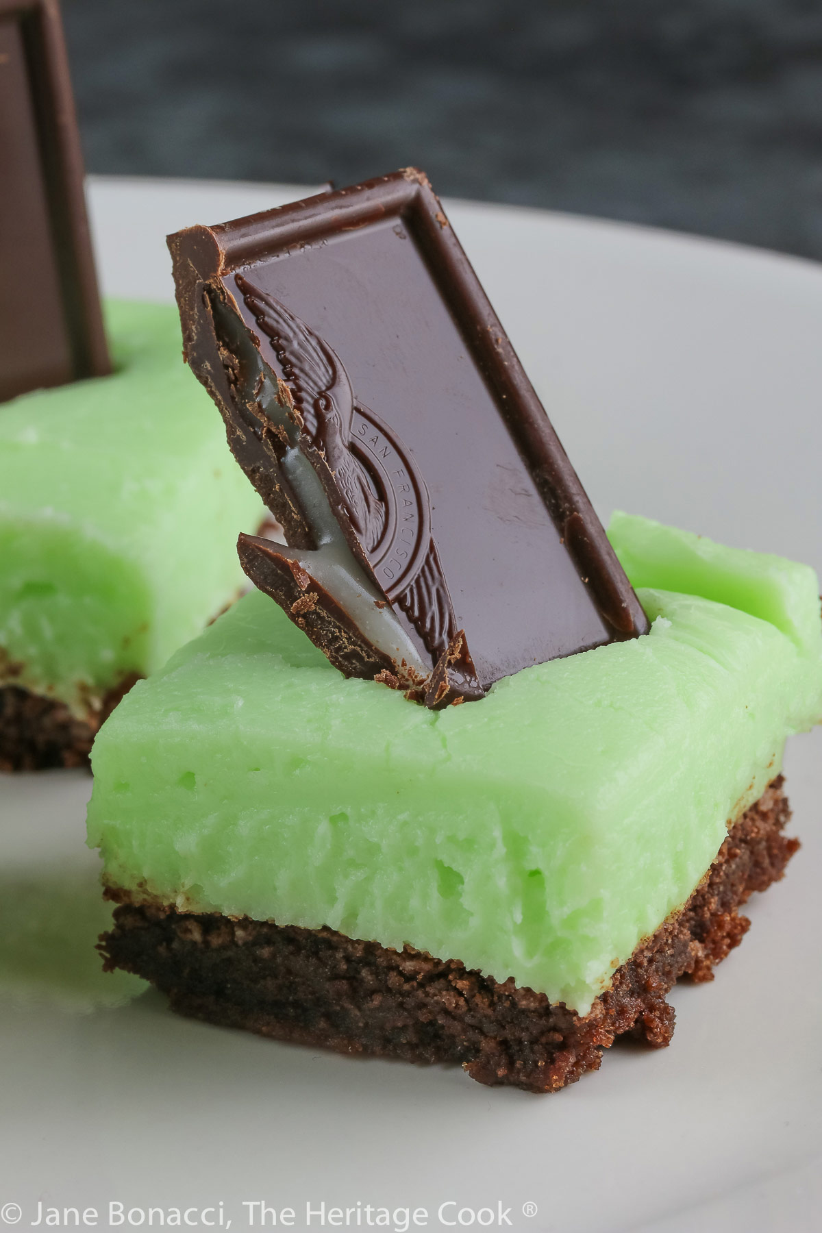 Brownies topped with pale green frosting with a chocolate-covered mint candy stuck in the top; Minty Chocolate Brownies © 2022 Jane Bonacci, The Heritage Cook. 