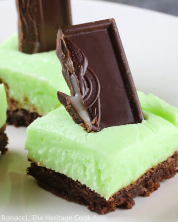 Brownies topped with pale green frosting with a chocolate-covered mint candy stuck in the top; Minty Chocolate Brownies © 2022 Jane Bonacci, The Heritage Cook.