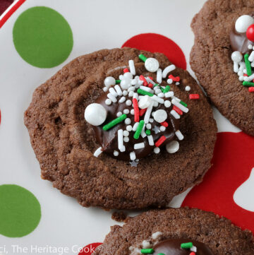 Small cookie cups filled with mint chocolate ganache and topped with festive holiday sprinkles; Hot Chocolate Mint Thumbprint Cookies © 2022 Jane Bonacci, The Heritage Cook.