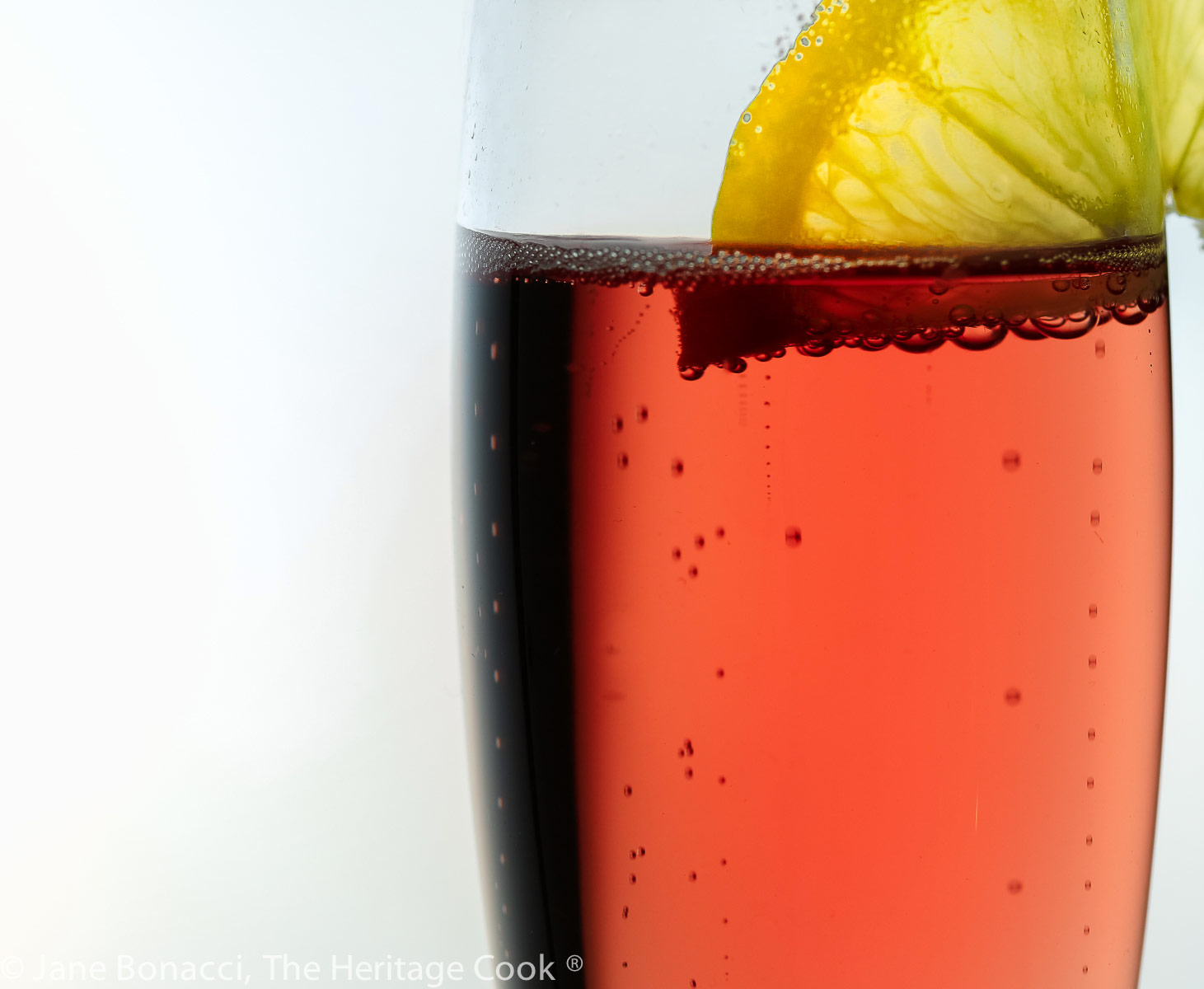 close up of kir royale with lemon slice on the edge of the glass. 