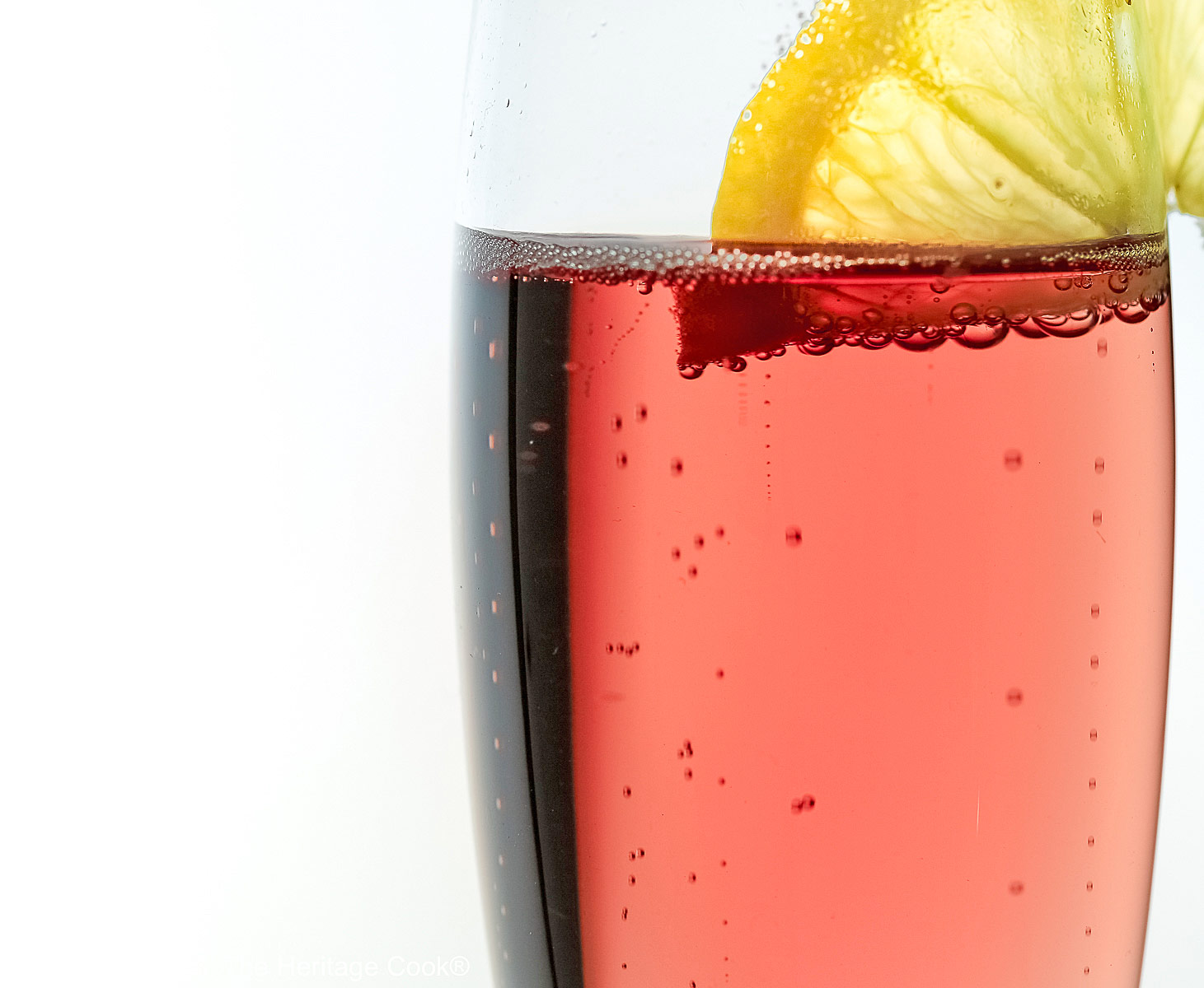 Kir Royale Champagne Cocktails are made with ruby red crème de cassis (black currant liqueur) combined with champagne to make these beautiful pink cocktails, served in crystal flutes on a white background © 2025 Jane Bonacci, The Heritage Cook.