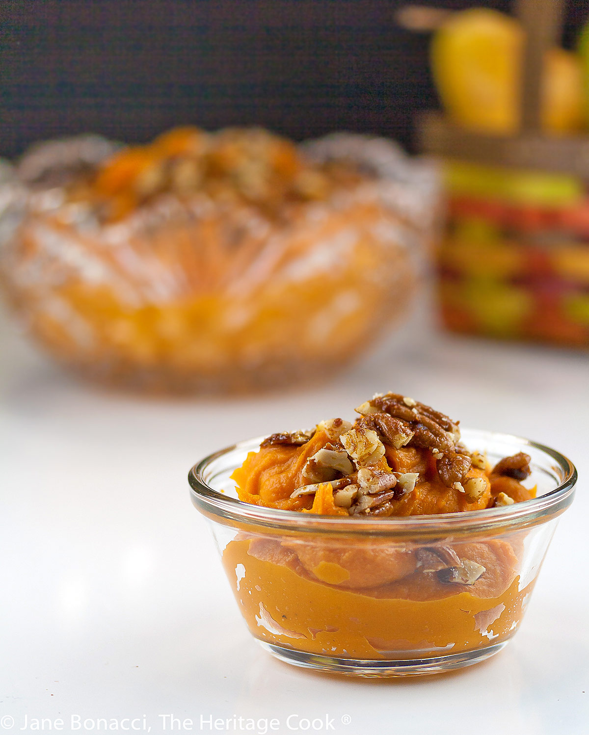 Maple whipped sweet potatoes topped with candied chopped pecans in two bowls, one cut glass; Maple Whipped Sweet Potatoes © 2022 Jane Bonacci, The Heritage Cook. 