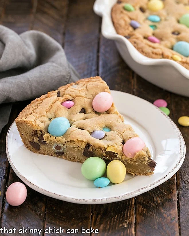Wedge of chocolate chip cookie with pastel Easter candies on top; 21 different chocolate treats in this blog post round-up are swoon-worthy; 21 Chocolate Easter Treats round-up 2023; assembled by Jane Bonacci, The Heritage Cook. 