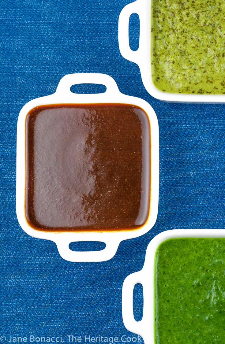 focus on the deep red BBQ sauce in a small white container on a blue background.