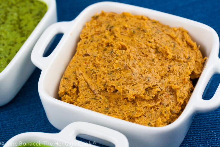 close up of the smoky spicy salsa compound butter in white container on a blue background.