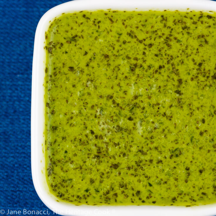 Zesty Cilantro-Chile Sauce in small white bowl on blue background.