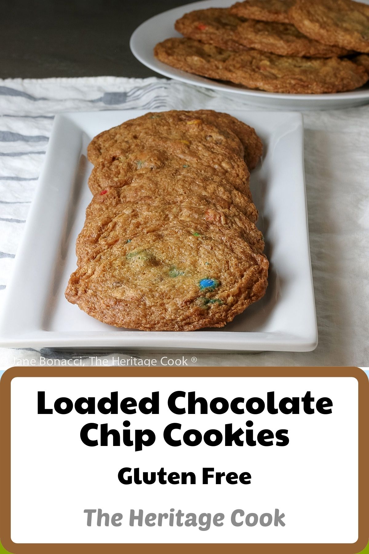 Line of shingled 4-inch cookies on rectangular white platter with plate piled with cookies in the back; Loaded Chocolate Chip Cookies © 2023 Jane Bonacci, The Heritage Cook.